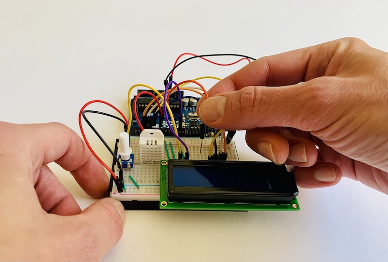 Hände beim Aufbau einer Arduino-Schaltung